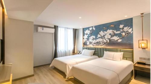 two beds in a hotel room with a painting on the wall at Magnotel Hotel Suzhou Shiquan Street Wangshiyuan in Suzhou