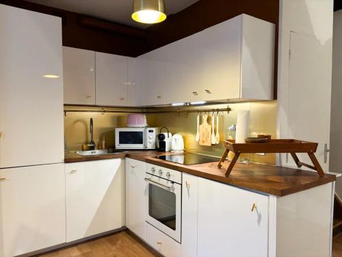 une cuisine avec des armoires blanches et une table à l'intérieur dans l'établissement Charmant duplex au calme 