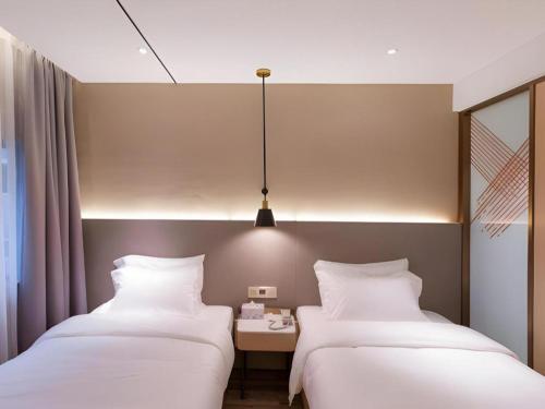 two beds in a hotel room with white pillows at ZMAX Hotels Shenzhen Lianhuacun Metro Station in Shenzhen