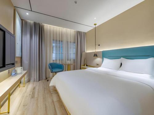 a hotel room with a large bed and a blue chair at ZMAX Hotels Shenzhen Lianhuacun Metro Station in Shenzhen