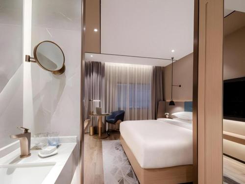 a hotel room with a bed and a sink and a mirror at ZMAX Hotels Shenzhen Lianhuacun Metro Station in Shenzhen