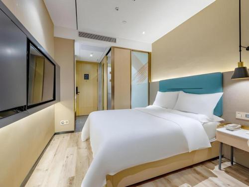 a bedroom with a large white bed and a television at ZMAX Hotels Shenzhen Lianhuacun Metro Station in Shenzhen