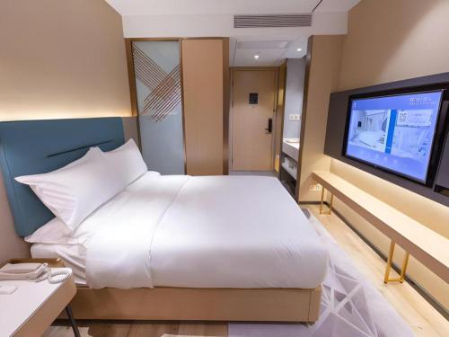 a bedroom with a white bed and a flat screen tv at ZMAX Hotels Shenzhen Lianhuacun Metro Station in Shenzhen