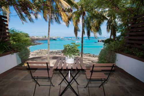 a table and chairs with a view of the ocean at Golden Bay Galapagos in Puerto Baquerizo Moreno