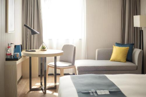 a hotel room with a bed and a table and a chair at Echarm Hotel Shenzhen World Exhibition and Convention Center in Shenzhen