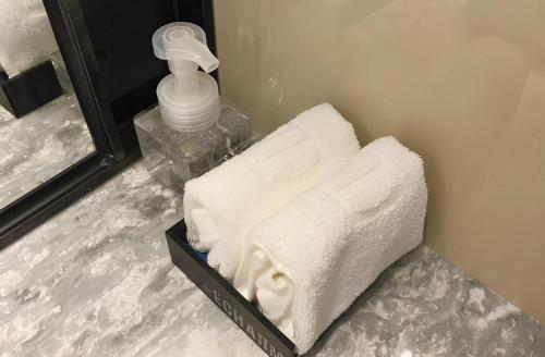a pile of towels sitting on a counter next to a mirror at Echarm Hotel Shenzhen World Exhibition and Convention Center in Shenzhen