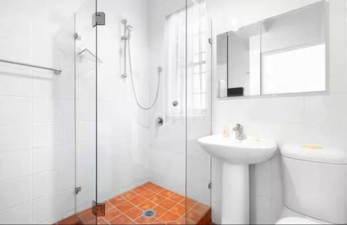 a white bathroom with a sink and a shower at Carnarvon Lodge Kirribilli, Sydney in Sydney
