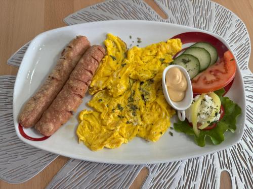 a plate of breakfast food with sausage and vegetables at Wooden Lakefront Bungalow in Jablanica