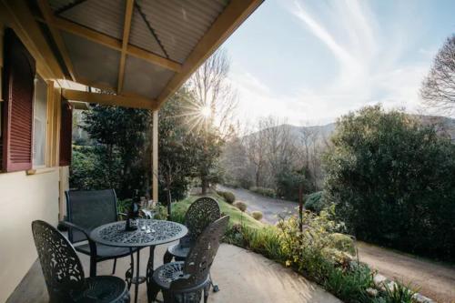 a patio with a table and chairs and a river at Chestnut Tree Holiday Units in Bright