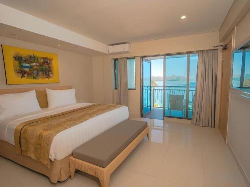 a bedroom with a large bed and a balcony at Laprima Hotel in Labuan Bajo