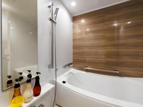 a bathroom with a bath tub with bottles on a shelf at Hotel Dream Gate Maihama Annex in Chiba