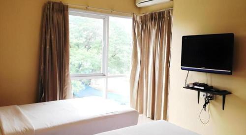 a bedroom with a bed and a tv and a window at C2 Residence Hotel in Lampang