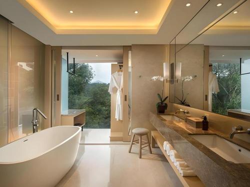 a bathroom with a large tub and a large mirror at Padma Hotel Bandung in Bandung