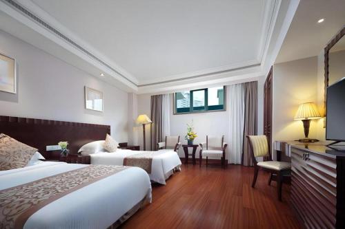 a hotel room with two beds and a television at Sanya Baohong Hotel in Sanya