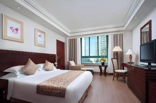 a hotel room with a bed and a television at Sanya Baohong Hotel in Sanya