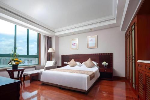 a bedroom with a large white bed and a desk at Sanya Baohong Hotel in Sanya