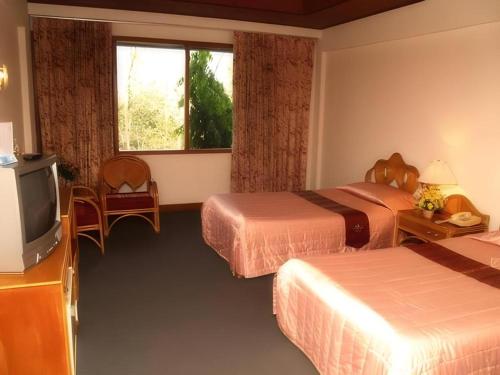 a hotel room with two beds and a television at Pailyn Hotel in Sukhothai