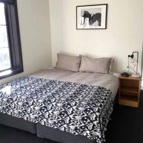 a bedroom with a bed with a black and white comforter at House of Ullr in Thredbo