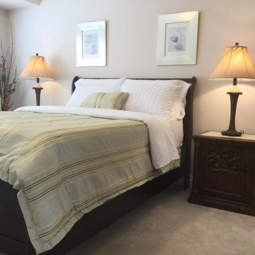 a bedroom with a bed and two lamps on tables at Vancouver Pacific Guest House in Richmond