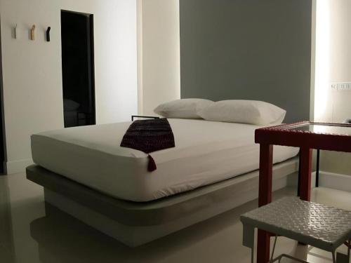 a bed with white sheets and pillows in a room at 189 Resort in Ban Khlong Samrong
