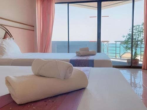 zwei Betten in einem Zimmer mit großen Fenstern in der Unterkunft Supar Royal Beach Hotel in Ban Plau