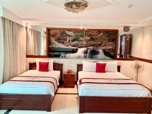 two beds in a room with a painting on the wall at Ha Oanh Hotel in Ho Chi Minh City
