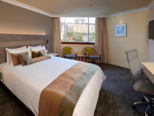 a hotel room with a large bed and a desk at Hotel Miramar Singapore in Singapore