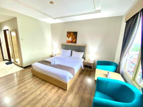 a hotel room with a bed and a blue chair at Orchardz Hotel Gajah Mada in Pontianak