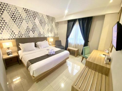 a hotel room with a bed and a bench at Orchardz Hotel Gajah Mada in Pontianak