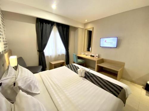 a hotel room with a bed and a television at Orchardz Hotel Gajah Mada in Pontianak