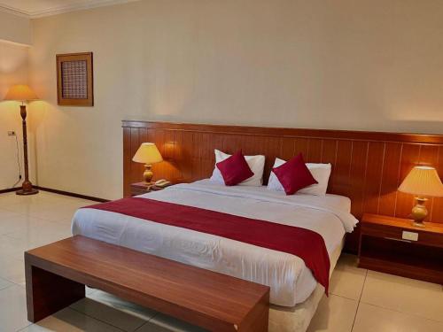 a bedroom with a large bed with red pillows at Garuda Hotel Pontianak in Pontianak