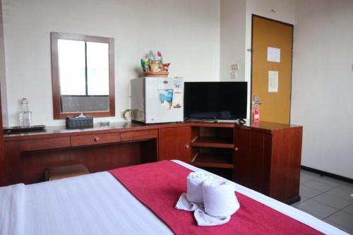 a bedroom with a bed and a desk with a television at Garuda Hotel Pontianak in Pontianak