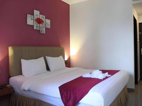 a bedroom with a large bed with a red wall at Garuda Hotel Pontianak in Pontianak