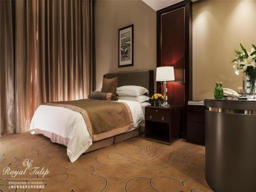 a bedroom with a bed and a table with a lamp at Royal Tulip Hotel Zhujiajiao Shanghai in Shanghai
