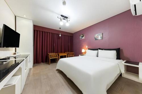 a bedroom with a large white bed and a purple wall at BENIKEA Technovalley Hotel in Daejeon