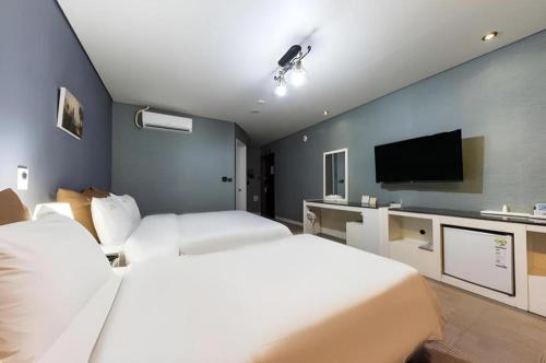 a hotel room with two beds and a flat screen tv at BENIKEA Technovalley Hotel in Daejeon