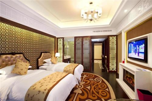 a bedroom with two beds and a television and a chandelier at Eden Club House in Tongxiang