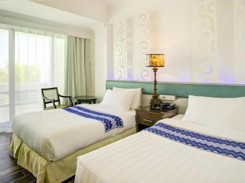 a hotel room with two beds and a window at Vitalis White Sands in Vigan
