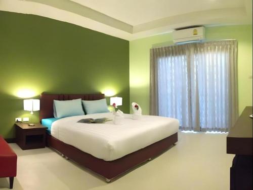 a bedroom with a large bed with green walls at Villa Thiwa Hotel in Ban Na Po Tai