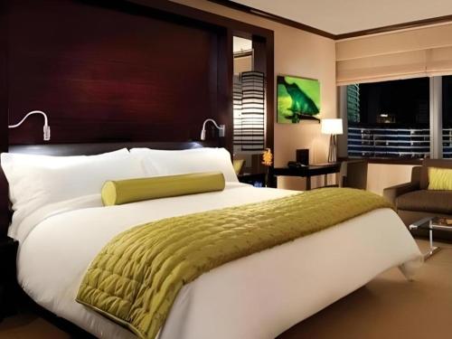 a bedroom with a large white bed with a green blanket at Luxury Suites International by Vdara in Las Vegas