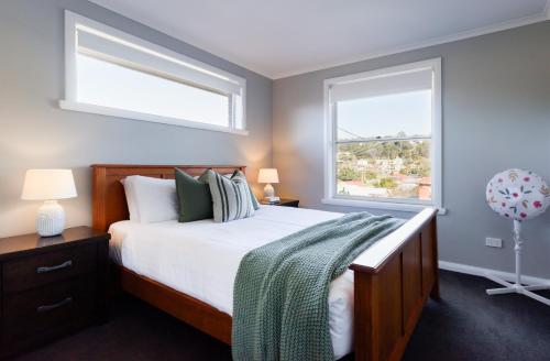 a bedroom with a bed and two windows at A Whole Lot Of House W/ Dual Living & Library in Inveresk