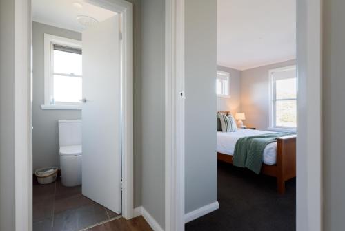 a bedroom with a bed and a toilet and two windows at A Whole Lot Of House W/ Dual Living & Library in Inveresk