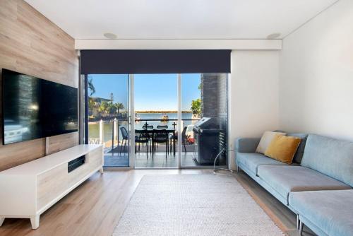 a living room with a couch and a flat screen tv at Waterfront Oasis in Runaway Bay - CoastHM in Gold Coast