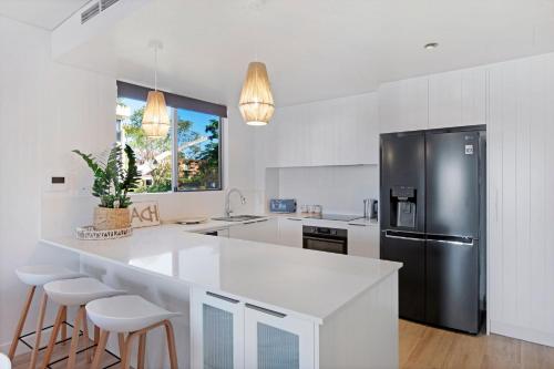 a kitchen with a black refrigerator and white cabinets at Waterfront Oasis in Runaway Bay - CoastHM in Gold Coast