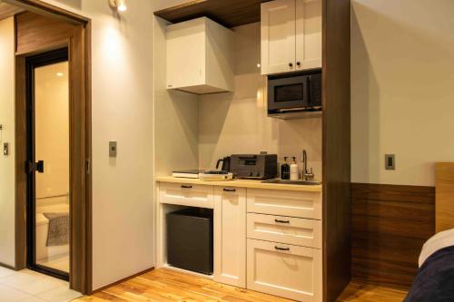 a kitchen with white cabinets and a microwave at blue in green 飯田高原 cottage and cafe in Iida