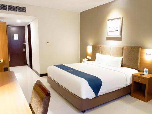 a bedroom with a large bed and a chair at Grage Hotel Cirebon in Cirebon