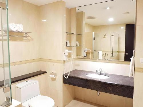 a bathroom with a toilet and a sink and a mirror at Grage Hotel Cirebon in Cirebon
