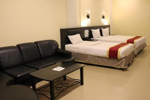a hotel room with two beds and a couch at Balai View Hotel in Tanjung Balai Karimun