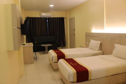 a hotel room with two beds and a television at Balai View Hotel in Tanjung Balai Karimun