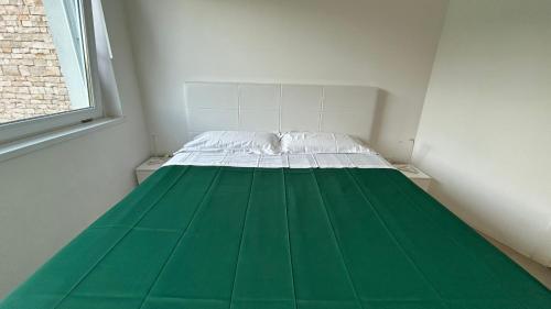 a small room with a green and white bed at Le Villette in Cittadella del Capo